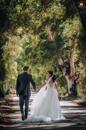 Newlyweds walk to their reception venue in the Incoronata forest near Foggia, Puglia. The photo shows the couple in a natural setting. The venue is visible in the distance.